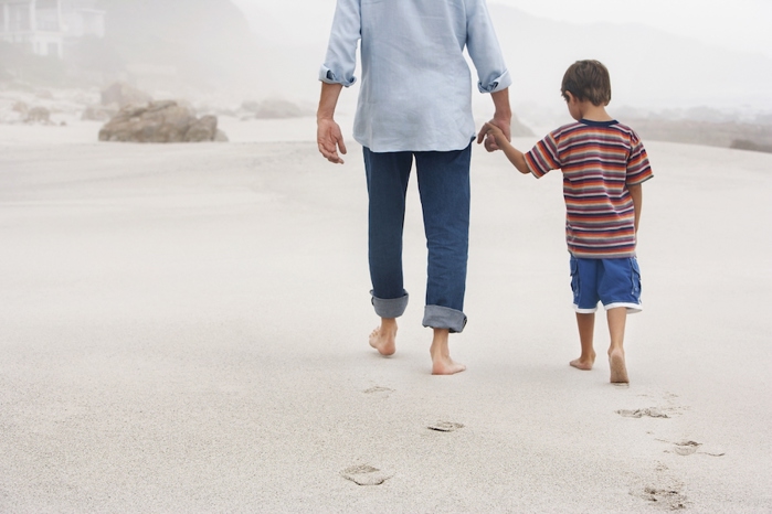 Father and son walking on beach.