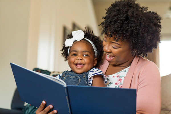 Woman reading a book to a young girl.