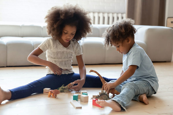 A sister and brother playing with toy blocks.