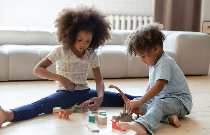 A sister and brother playing with toy blocks.