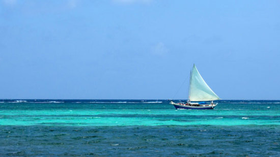 A boat sailing on a blue ocean with a blue sky.